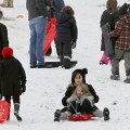 Tim Burton and Helena Bonham Carter take advantage of the snowfall in London by sledding with their kids on Primrose Hill.