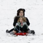 Tim Burton and Helena Bonham Carter take advantage of the snowfall in London by sledding with their kids on Primrose Hill.