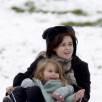 Tim Burton and Helena Bonham Carter take advantage of the snowfall in London by sledding with their kids on Primrose Hill.