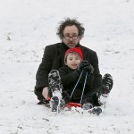Tim Burton and Helena Bonham Carter take advantage of the snowfall in London by sledding with their kids on Primrose Hill.
