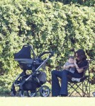 Victoria Beckham keeps baby Harper in the shade while they watch the boys playing soccer .
