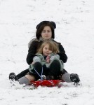 Tim Burton and Helena Bonham Carter take advantage of the snowfall in London by sledding with their kids on Primrose Hill.