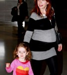 Alyson Hannigan shows off a huge baby bump as she arrives at JFK Airport in New York with husband Alexis Denisof and daughter Satyana.