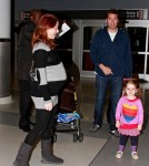 Alyson Hannigan shows off a huge baby bump as she arrives at JFK Airport in New York with husband Alexis Denisof and daughter Satyana.